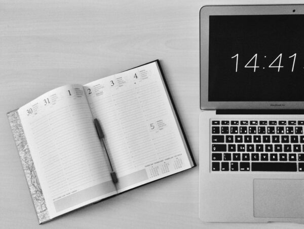 Flat Lay Photography of Unfold Book Beside Macbook